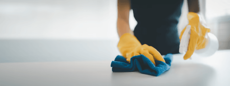 Gloved hand wiping down a home surface during a recurring house cleaning
